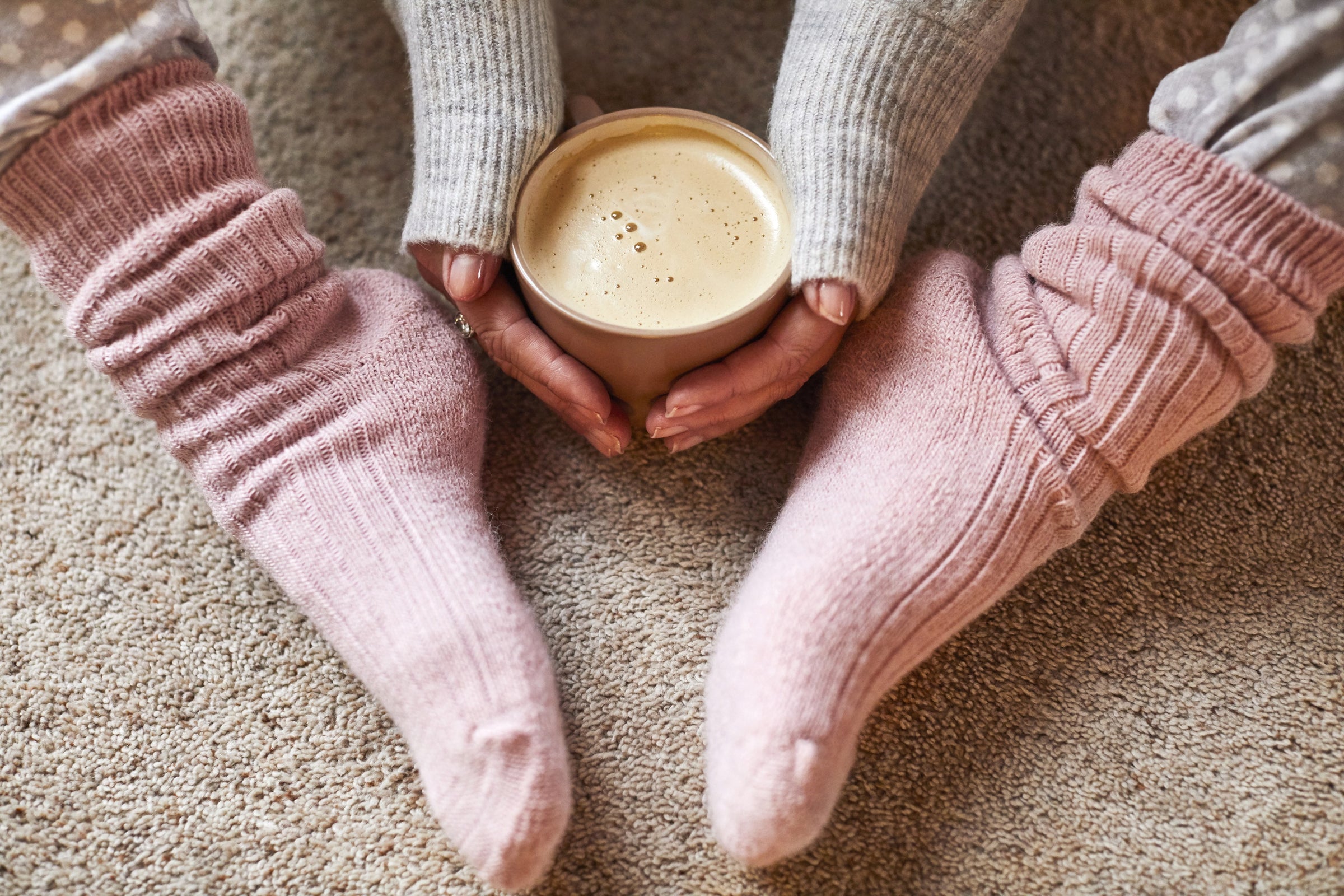 Cozy pink wool socks holding a warm coffee mug
